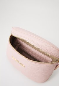 Rozā ādas soma ar zelta elementiem, ar apaļu dizainu, ar rāvējslēdzēju un iekšējo rāvējslēdzēja kabatu. "Valentino" logo iegravēts priekšpusē.