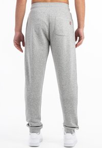 Grå sweatpants lavet af blødt stof, med en tætsiddende manchet ved anklen og en baglomme med en lille logodetalje.