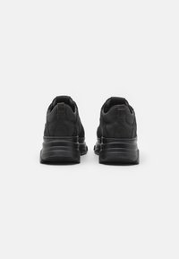 Chaussures de sport noires au design élégant, en daim texturé, avec une semelle rembourrée et un talon renforcé équipé d'une languette de traction.