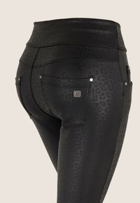 Leggings negras con un sutil estampado de leopardo, cintura alta, bolsillos traseros y detalles en hardware de tono plateado. Textura suave y diseño ajustado.