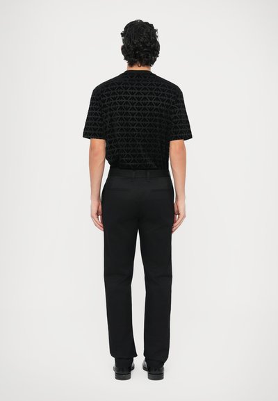 Čierna košeľa s krátkym rukávom s geometrickým textúrovaným vzorom, v kombinácii s čiernymi nohavicami. Jednoduchý dizajn, jednotná farebná schéma a rovný strih.