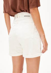 Valkoiset farkkushortsit, joissa on käännettävät reunokset, keskikorkea vyötärö ja kaksi takataskua. Vyötärönauhassa lukee "ARMEDANGELS".