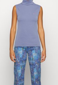 Ärm- och halslös topp i ljuslila bomullstyg. Har en liten logo på bröstet och en smal passform. Matchas med mönstrade blå byxor.