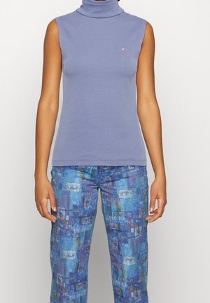 Top senza maniche con collo alto in cotone leggero di colore viola. Presenta un piccolo logo sul petto e una vestibilità aderente. Abbinato a pantaloni blu con motivo.
