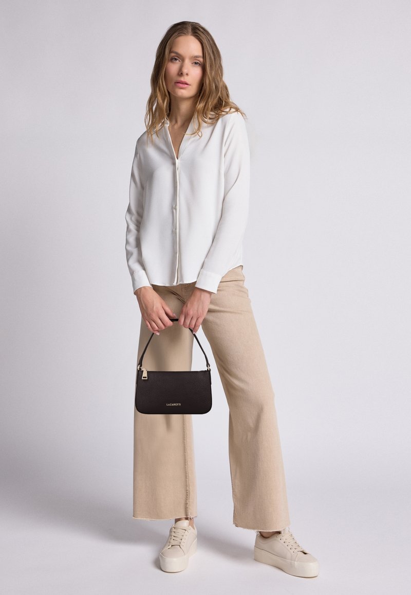 Camicia bianca a maniche lunghe con bottoni, pantaloni beige a gamba larga, borsa nera texturizzata e sneakers chiare. Design semplice e pulito con colori a contrasto.