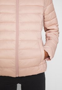 Helle rosa Pufferjacke mit horizontaler Steppung, durchgehendem Reißverschluss und seitlichen Taschen. Glatte Textur und taillierte Passform. Geeignet für kühle Wetter.