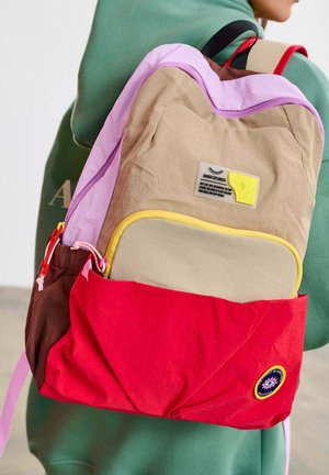 Kolorowy plecak z beżowymi, różowymi, brązowymi i czerwonymi sekcjami. Tkanina o fakturze z naszywką z logo i ozdobnymi zamkami. Regulowane paski.