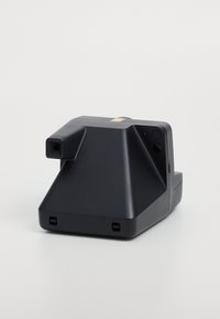 Črni instant fotoaparat, ki se ponaša z geometričnim oblikovanjem, teksturiranim oprijemom in lečo. Vključuje gumbne kontrole in pisan trak na vrhu.