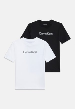 Deux T-shirts manches courtes col rond, un blanc et un noir, chacun avec le texte "Calvin Klein" centré sur le devant.