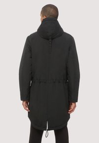 Abrigo negro largo acolchado con capucha, cintura ajustable con cordón y dobladillo curvado. Fabricado con tela suave y resistente al agua, con detalles mínimos.