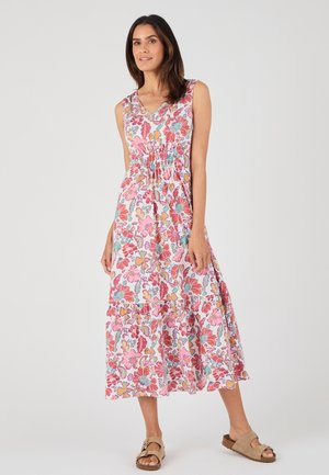 Vestido maxi floral con un fondo rosa y flores multicolores, cintura fruncida y falda en capas. Combinado con sandalias beige.
