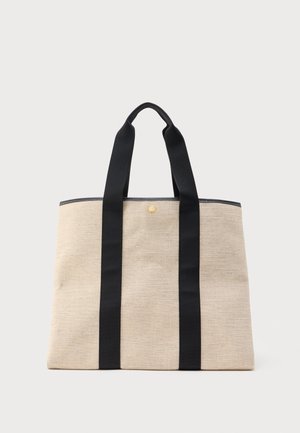 Beežist riidest kandekott kahe laia musta käepidemega, mis ulatuvad vertikaalselt koti esiküljel, ning väike ümar kuldne nupp koti ülaosa keskpaigas.