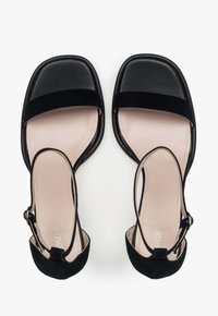 Zwarte sandalen met een vierkante neuzenontwerp, voorzien van een zachte suède band aan de voorkant en een achterste enkelband met een gespsluiting.
