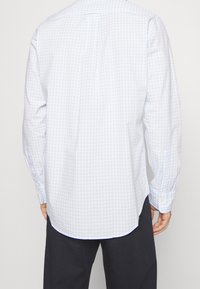 Světle modrá kostkovaná košile s dlouhým rukávem vyrobená z bavlny, s límečkem na tlačítka, jedním vodorovným skladem na zádech a manžetami na knoflíky.