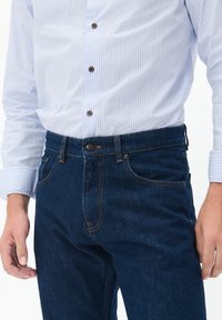 Tumesinised denim püksid sirge lõikega, millel on oranž õmblus, esi-taskud ja nipsuga kinnitamine vööl.