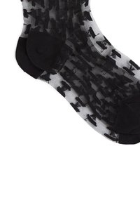 Calcetines negros transparentes que presentan un patrón texturizado de formas abstractas en negro, con secciones de puntera y talón sólidas en negro.