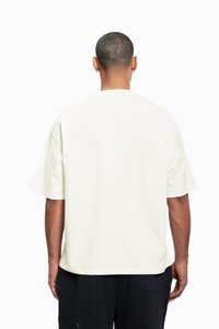 Relaxed-fit, short-sleeve t-shirt in pale cream cotton, featuring a simple design with a round neckline and no visible branding on the back.