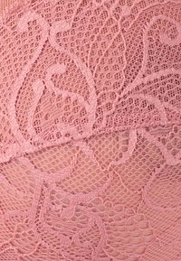 Tessuto di pizzo rosa con intricate fantasie floreali e swirl, caratterizzato da una trama aperta e testurizzata e bordi scallop.