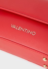 Borsa Red Valentino in materiale testurizzato, con logo dorato, forma rettangolare e due borchie dorate sui lati.