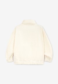 Krémově zbarvená volná bunda s límcem, elastickými manžetami a texturovanou látkou s jemným vyraženým vzorem.
