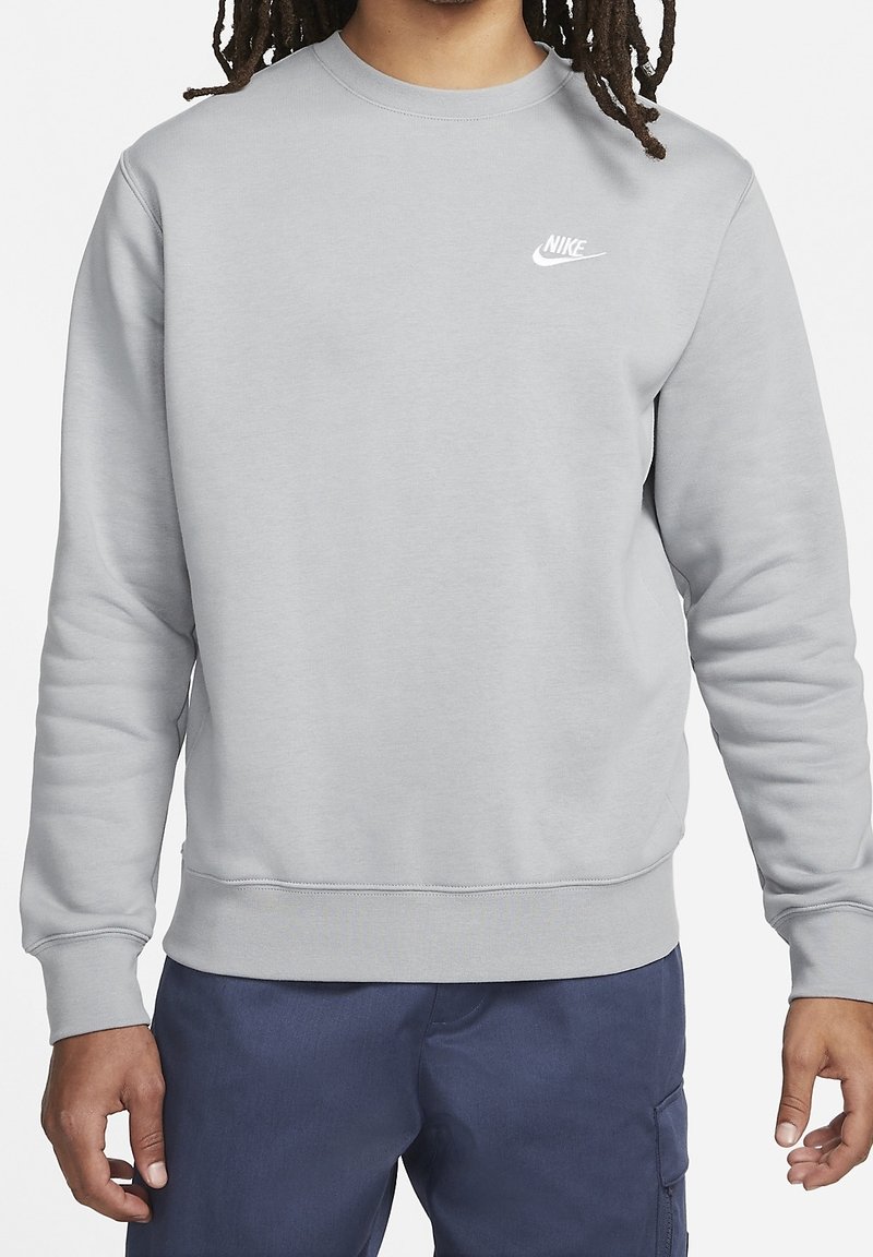 Gray fleece sweatshirt with round neckline, ribbed cuffs, and hem. Features a small white Nike logo on the left chest. Soft texture.