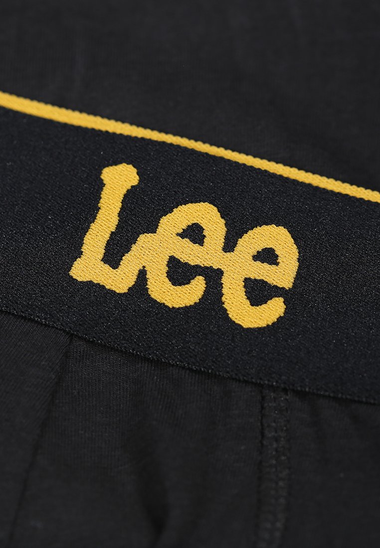 Czarny materiał pasa z widocznym, żółtym haftowanym logo "Lee". Gładka faktura z kontrastującym, żółtym paskiem na górze.