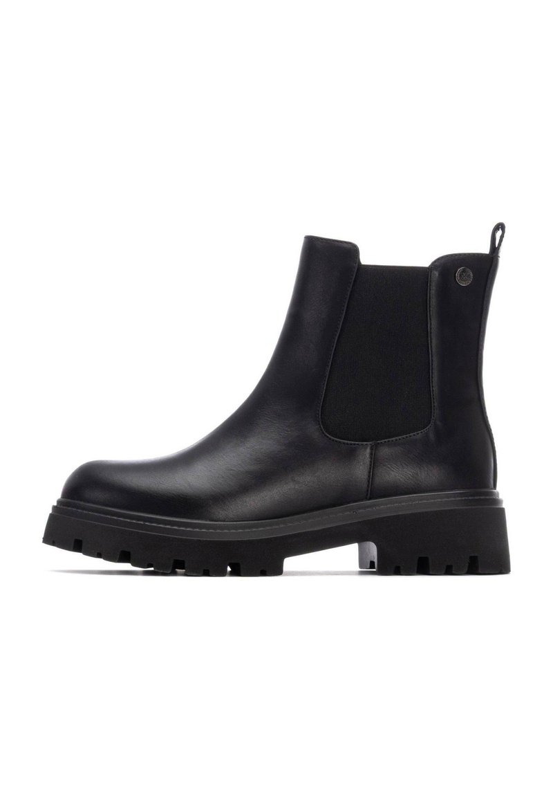 Botas Chelsea de cuero negro con paneles laterales elásticos, suela de goma plana y tirador. Presenta una textura suave y un diseño de puntera redondeada.