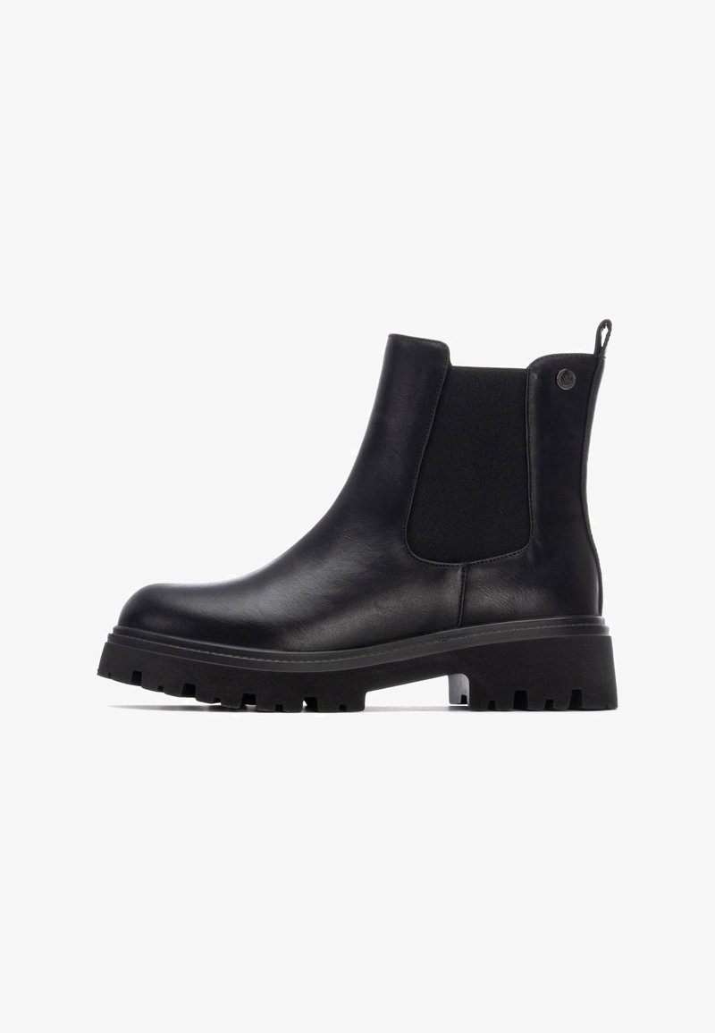 Botas Chelsea de cuero negro con paneles laterales elásticos, suela de goma plana y tirador. Presenta una textura suave y un diseño de puntera redondeada.