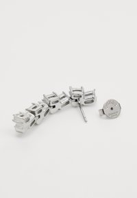 Sidabrinis metalo plaukų aksesuaras su keliais tarpusavyje susijungiančiais elementais ir apvaliu užsegimu, pažymėtu "GUESS Stainless Steel". Lygaus paviršiaus ir modernaus dizaino.