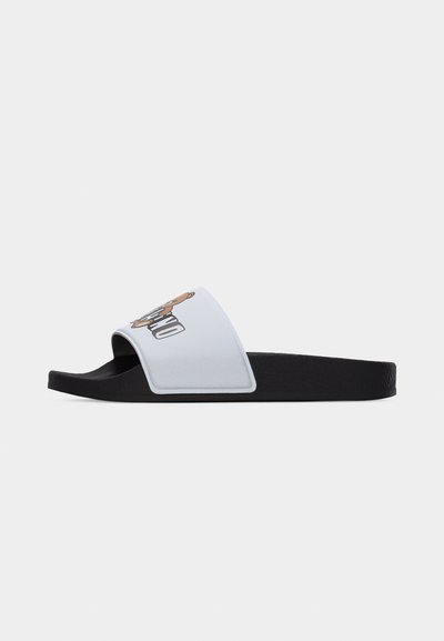 Μαύρο σανδάλι με λευκό λουρί που έχει γραφικό με αρκουδάκι και έντονο κείμενο στην κορυφή, φαίνεται από το πλάι.