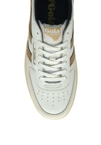 Sneaker bianco e beige realizzato in pelle e suede, con punta forata, lacci bianchi e un logo sulla linguetta.