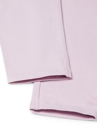 Primo piano di un tessuto rigato di un leggero colore viola piegato, con cuciture visibili e un piccolo logo ricamato vicino al bordo.