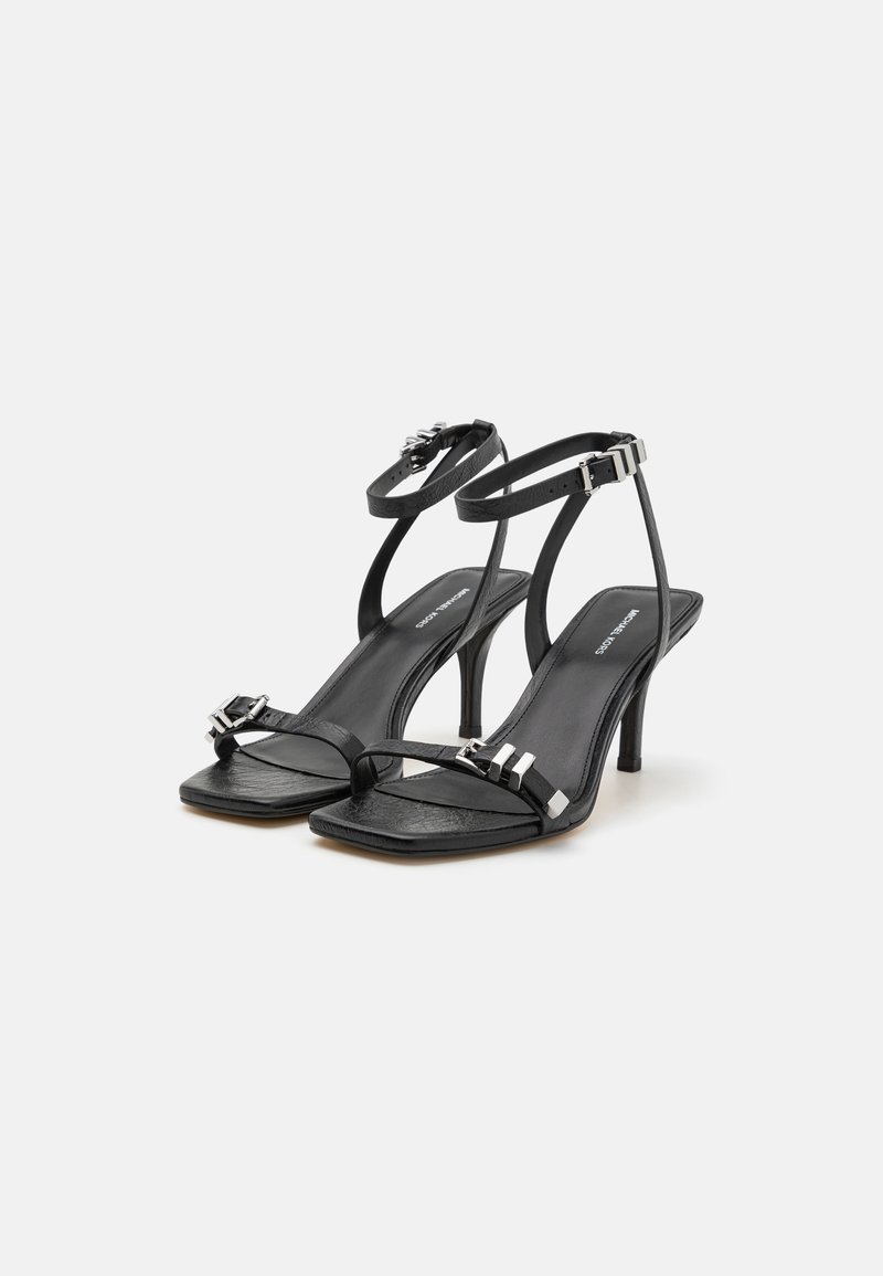 Sandali neri in pelle con tacco, dotati di sottili cinturini alla caviglia e sulla parte anteriore del piede, punta quadrata, dettagli metallici e un tacchi stiletto modesto.