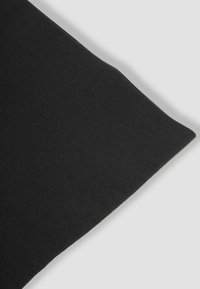 Tessuto nero a costine con una texture liscia; il bordo è rifinito in modo ordinato con un taglio pulito, evidenziando un design semplice e minimale.