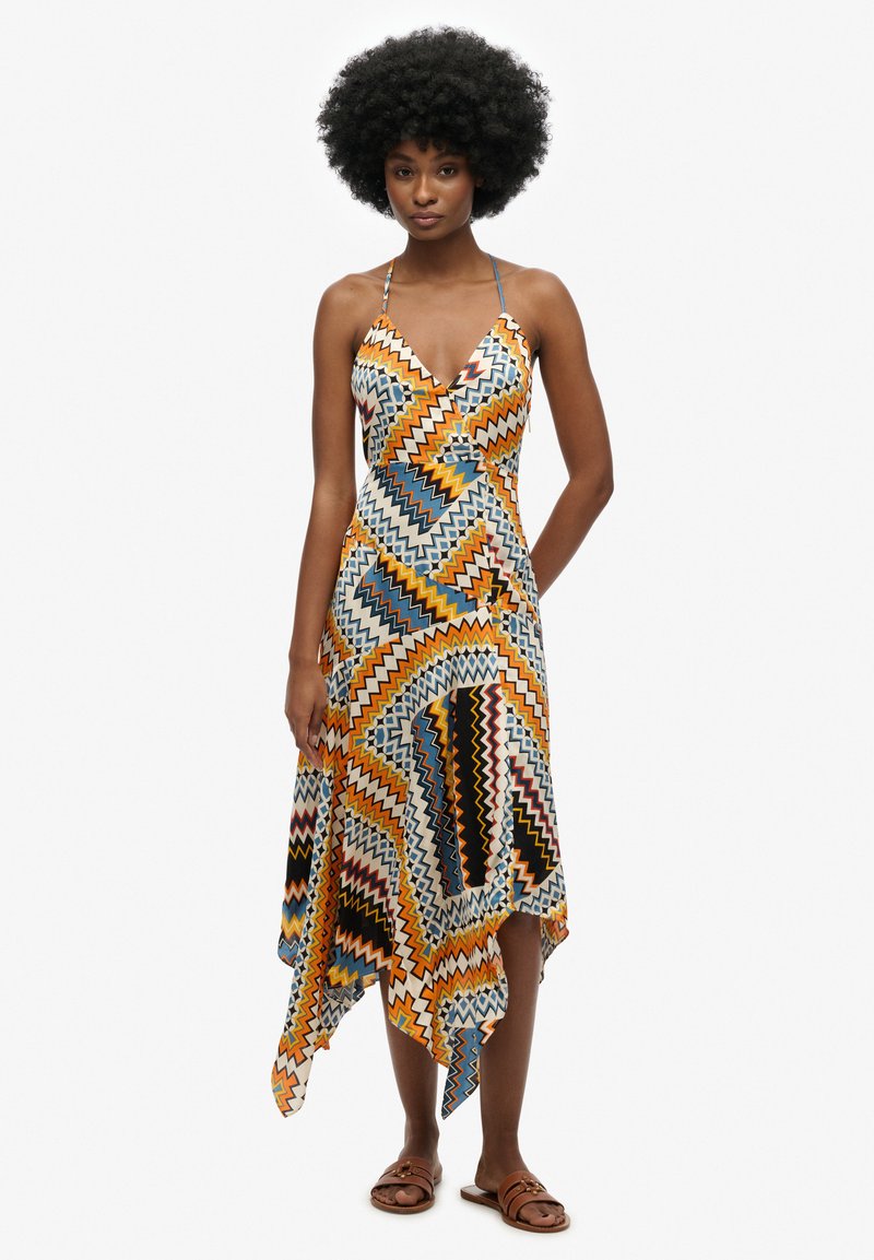 Vestido de patrones multicolores con escote en V y dobladillo asimétrico. Hecho de tela ligera con diseños en zigzag y geométricos.