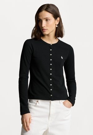 Cardigan noir à manches longues en tissu doux, avec un col rond, un bouton de fermeture et un petit logo brodé sur la poitrine.