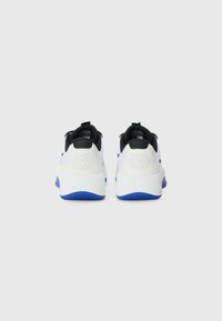 Baskets blanches de sport avec une finition texturée, des accents noirs et des semelles bleues. Présentent une languette à l'arrière et des détails perforés sur les côtés.