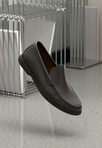 Tmavě šedá klouzavá bota vyrobená z texturované kůže s kulatou špičkou a detailem šití. Má nízkou gumovou podrážku a minimalistický design.
