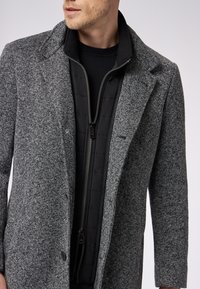 Grau karierten Überrock mit strukturiertem Kragen, ausgestattet mit einem schwarzen Reißverschluss-Innenfutter, strukturiertem Stoff und zwei Vorderknöpfen.