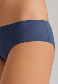 Tmavě modré bikiny s hladkou texturou, bezšvovým designem a nízkým pasem. Materiál je lehký a pružný.
