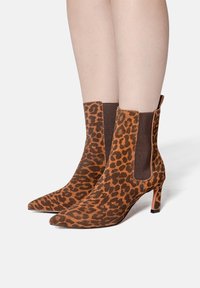 Leopard print ankle boots with a pointed toe, made of textured suede, featuring a slim heel and elastic side panels in brown.
