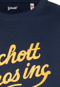 Felpa in cotone blu navy con un logo "Schott" grande e audace in giallo corsivo sul davanti, con scollo rotondo e trama a coste.