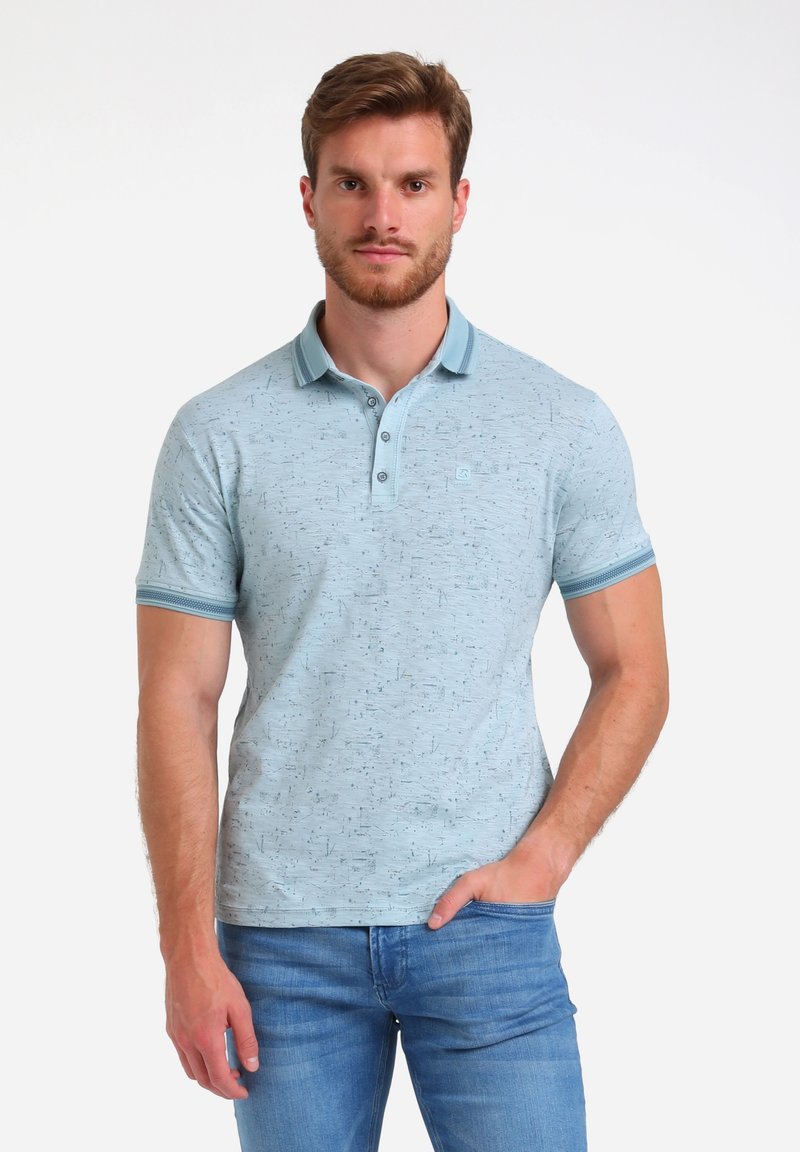 Camisa polo de color azul claro con un patrón texturizado, tres botones y rayas de color contrastante en el cuello y las mangas. Combinada con jeans de mezclilla azul.