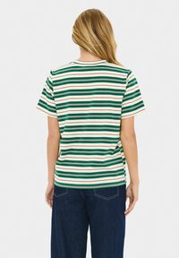 T-shirt rayé dans des teintes vert, crème et bourgogne. Manches courtes, col rond, coupe décontractée. Présente des rayures horizontales de largeurs variées.