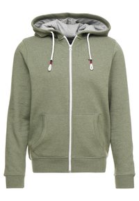 Olivgrüner Reißverschluss-Hoodie mit grauem Innenfutter, weißem Frontreißverschluss, zwei Fronttaschen und Kordeln mit roten und blauen Akzenten.