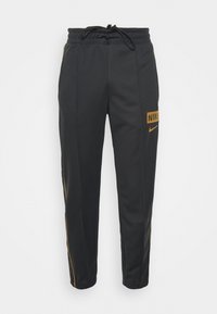 Svarta Nike träningbyxor med bruna sidostrick, elastiskt midjeband med dragsko och Nike-logotyp på vänster lår.