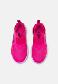 Des chaussures de sport slip-on rose vif avec des logos Nike noirs, des sangles élastiques sur le dessus et des semelles blanches sur un fond blanc.