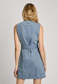 Abito senza maniche in denim blu chiaro, vita stretta con cintura, con dettagli delle cuciture e scollatura tonda. Tessuto morbido, lunghezza al ginocchio.