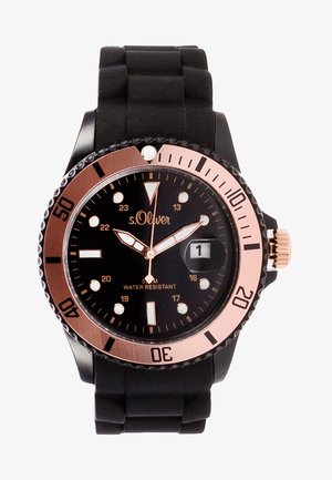 Montre noire avec lunette en or rose, aiguilles lumineuses, affichage de la date indiquant "1" et bracelet en silicone noir, étanche jusqu'à 5 ATM.
