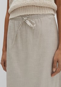 Beige Leinenrock mit elastischem Bund und Kordelzug. Der Stoff hat eine glatte Textur, und das Design weist keine sichtbaren Muster auf.